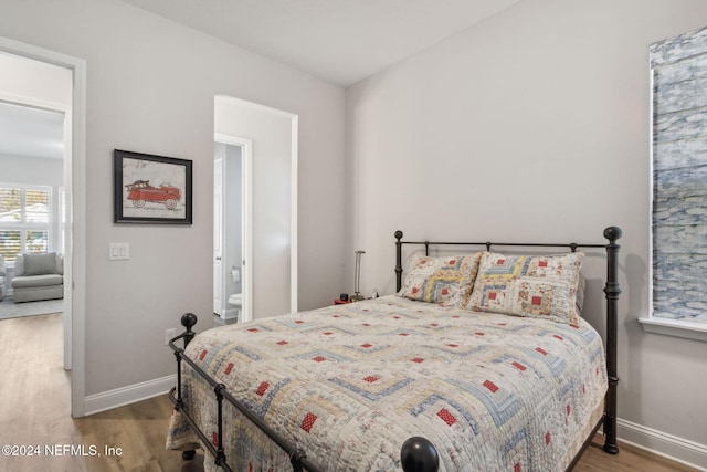 bedroom with wood-type flooring and ensuite bath