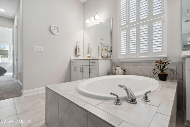 bathroom featuring tile patterned flooring, vanity, and tiled bath