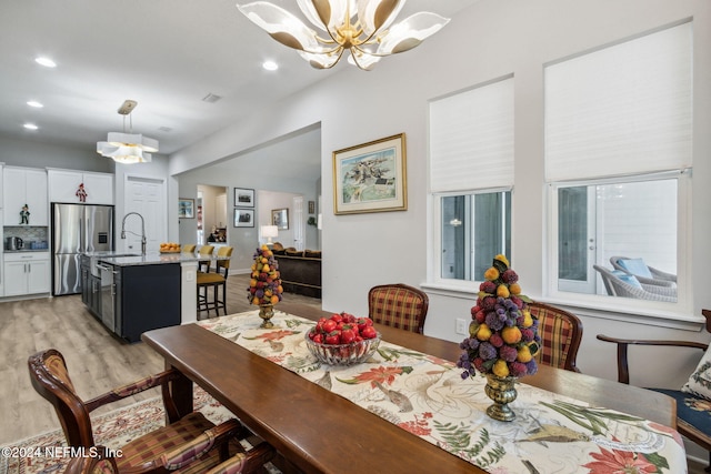 dining space with a chandelier, light hardwood / wood-style floors, and sink