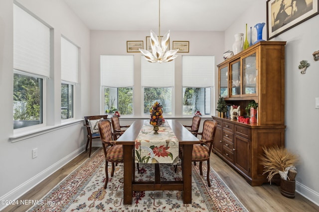 dining space featuring light wood-type flooring and an inviting chandelier