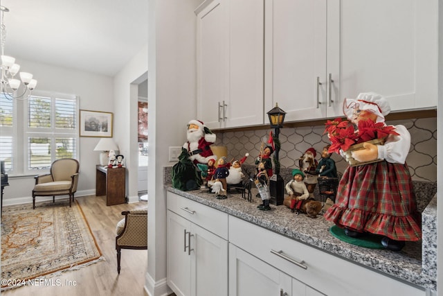 kitchen with light stone countertops, decorative backsplash, white cabinets, and light hardwood / wood-style floors