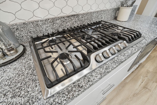 interior details with stainless steel gas stovetop, light wood-type flooring, and light stone countertops