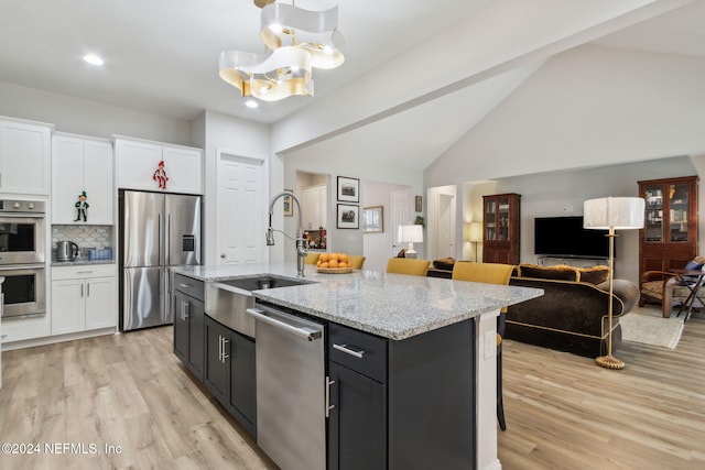 kitchen with white cabinetry, stainless steel appliances, a kitchen island with sink, a breakfast bar, and light wood-type flooring