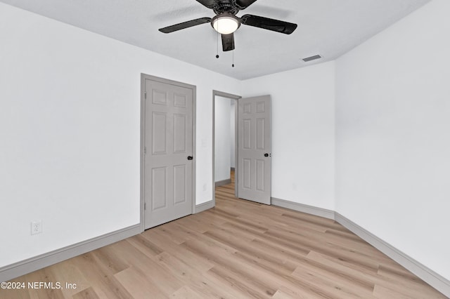 unfurnished room with light wood-style floors, baseboards, visible vents, and ceiling fan