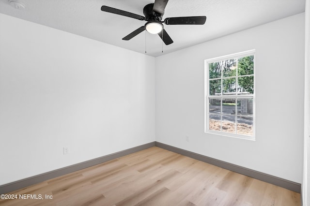 spare room with a textured ceiling, light wood-style flooring, and baseboards