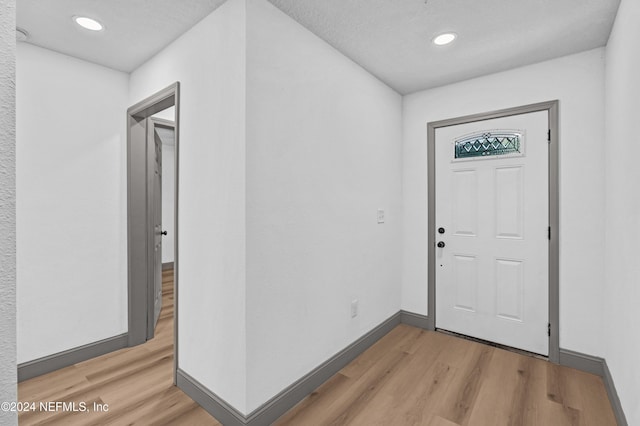 foyer featuring a textured ceiling, light wood finished floors, recessed lighting, and baseboards