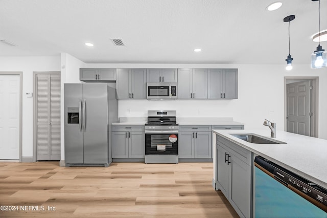 kitchen featuring visible vents, appliances with stainless steel finishes, gray cabinets, light countertops, and a sink