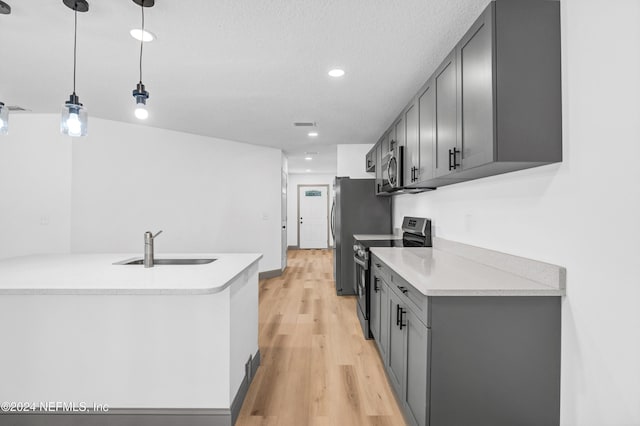 kitchen with light countertops, gray cabinetry, appliances with stainless steel finishes, light wood-style floors, and a sink