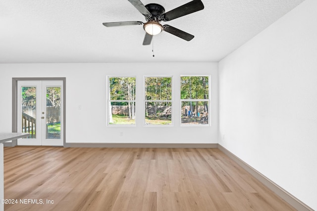 spare room with french doors, plenty of natural light, light wood-style flooring, and a textured ceiling