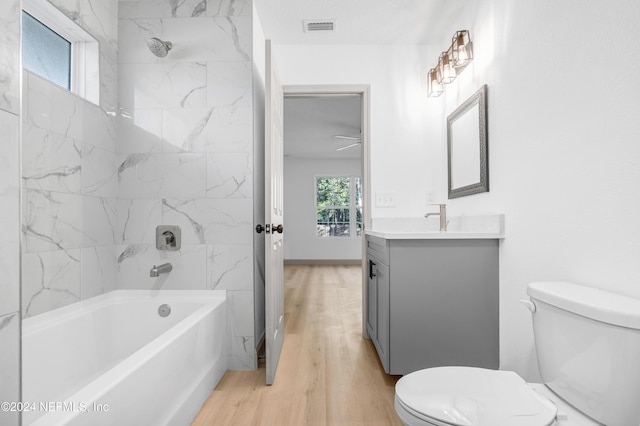 bathroom featuring visible vents, toilet, vanity, wood finished floors, and  shower combination