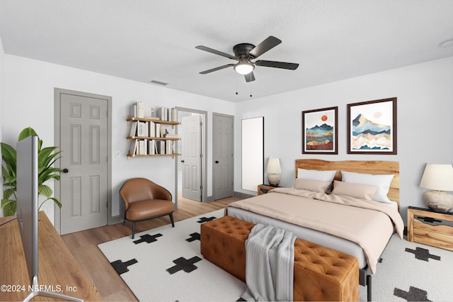 bedroom featuring light wood finished floors, visible vents, and a ceiling fan