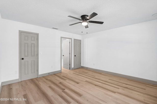 unfurnished bedroom featuring baseboards, visible vents, a ceiling fan, a textured ceiling, and light wood-style floors