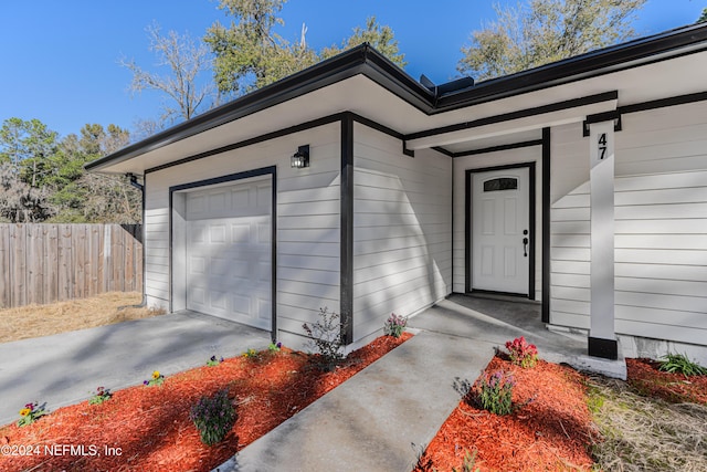 doorway to property with a garage and fence