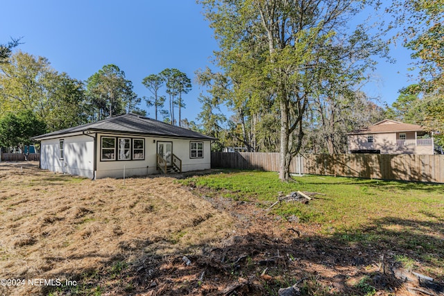 back of house featuring entry steps, a fenced backyard, and a lawn