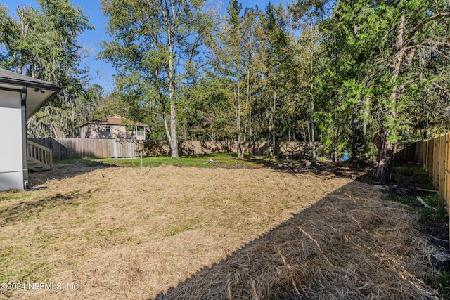 view of yard with a storage shed, a fenced backyard, and an outbuilding