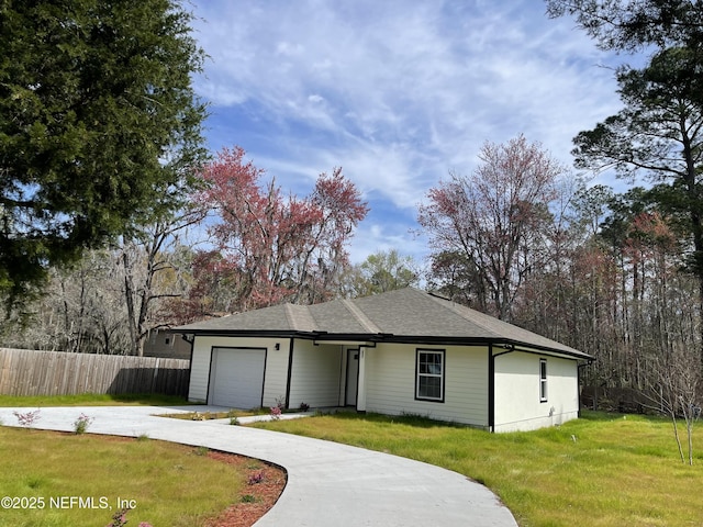 ranch-style home with an attached garage, fence, concrete driveway, roof with shingles, and a front yard