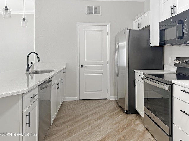 kitchen with appliances with stainless steel finishes, light wood-type flooring, decorative light fixtures, and white cabinetry