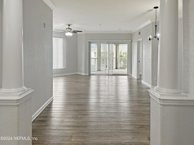 spare room featuring ceiling fan with notable chandelier, dark hardwood / wood-style floors, and decorative columns