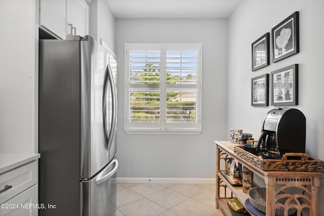 kitchen with white cabinetry, stainless steel fridge, and light tile patterned floors