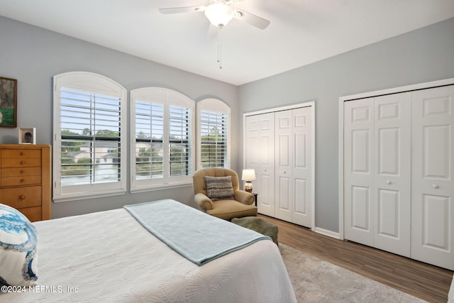 bedroom with ceiling fan, light hardwood / wood-style floors, and multiple closets