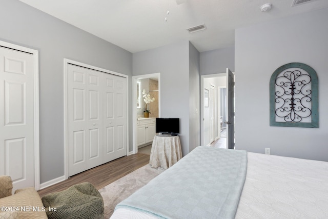 bedroom with connected bathroom and light hardwood / wood-style floors