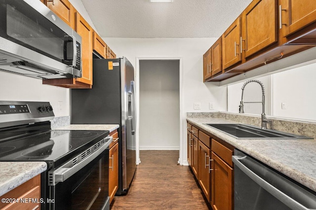 kitchen with dark wood-type flooring, stainless steel appliances, a textured ceiling, and sink