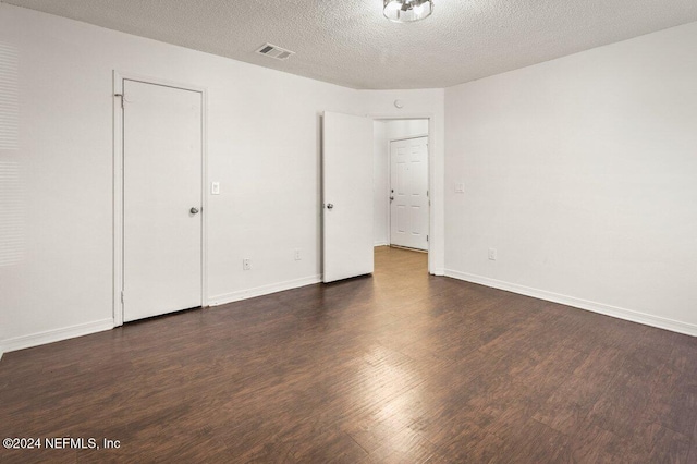 unfurnished room featuring a textured ceiling and dark wood-type flooring