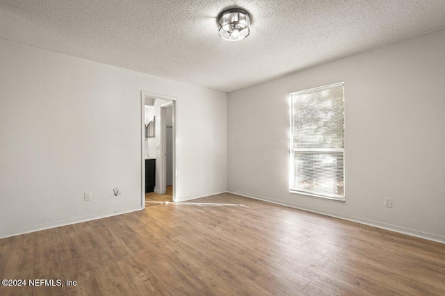 unfurnished room featuring a textured ceiling and light wood-type flooring