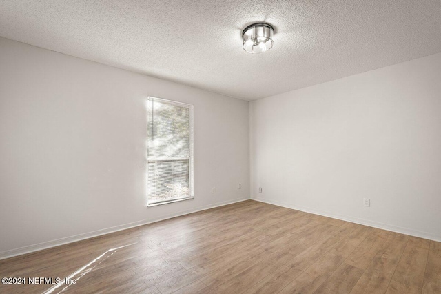 spare room featuring hardwood / wood-style flooring and a textured ceiling