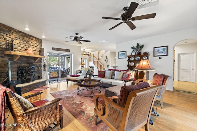 living room with ceiling fan, a fireplace, and light hardwood / wood-style floors