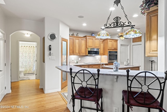 kitchen featuring sink, a breakfast bar area, light hardwood / wood-style flooring, tasteful backsplash, and stainless steel appliances