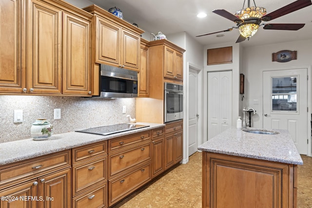 kitchen with a center island, sink, decorative backsplash, light stone countertops, and appliances with stainless steel finishes