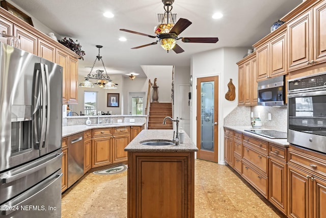 kitchen featuring sink, hanging light fixtures, backsplash, a kitchen island with sink, and appliances with stainless steel finishes