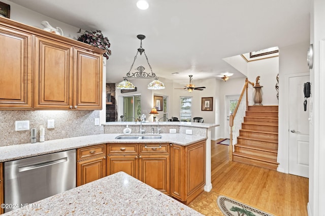 kitchen featuring stainless steel dishwasher, ceiling fan, sink, decorative light fixtures, and light hardwood / wood-style flooring