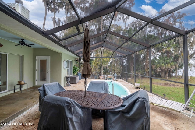 view of patio featuring ceiling fan and glass enclosure