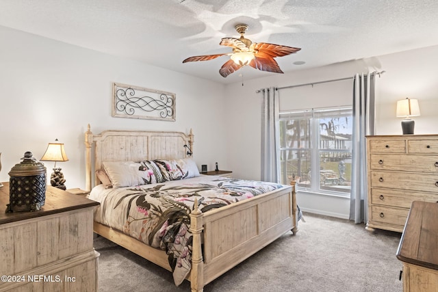 bedroom with ceiling fan, dark carpet, and a textured ceiling