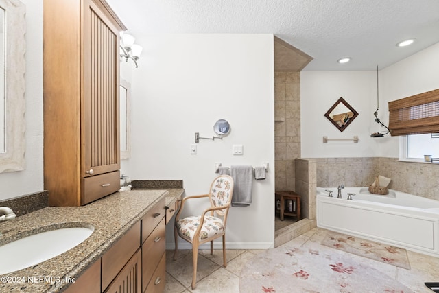 bathroom featuring a washtub, vanity, a textured ceiling, and tile patterned floors