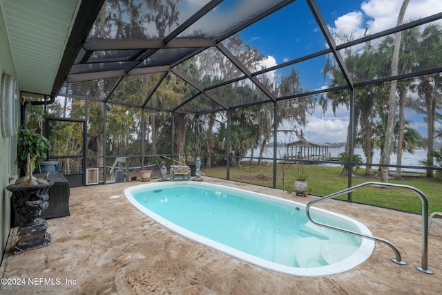 view of pool with a water view, glass enclosure, and a patio area