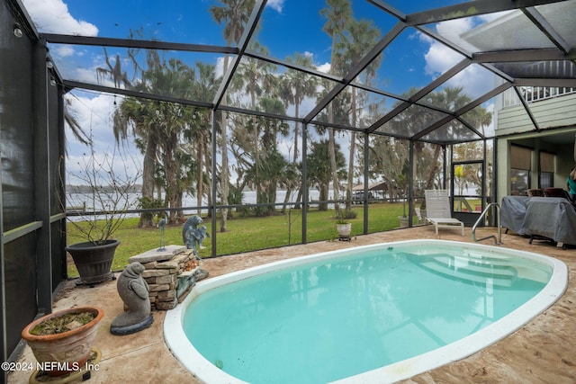 view of pool featuring a lawn, glass enclosure, and a patio area