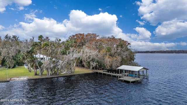 view of dock with a lawn and a water view