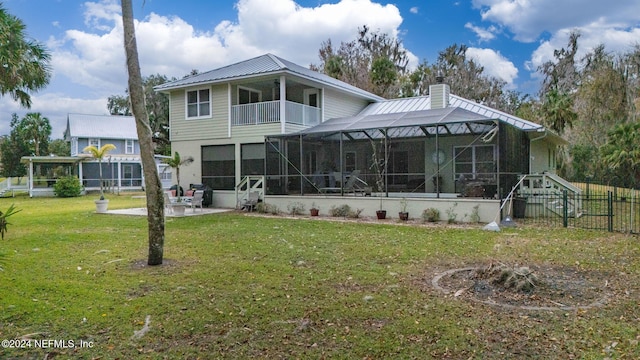 rear view of property featuring a yard, glass enclosure, a balcony, and a patio