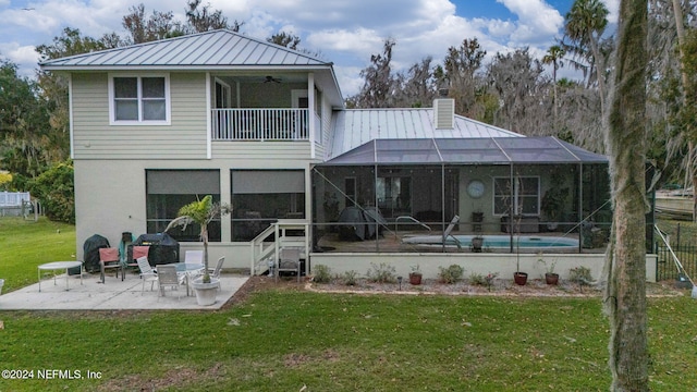 back of property with a balcony, a patio, a lanai, ceiling fan, and a yard