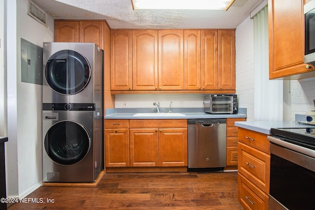 kitchen featuring sink, dark wood-type flooring, electric panel, stacked washer / drying machine, and appliances with stainless steel finishes