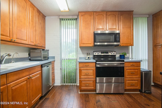 kitchen with dark hardwood / wood-style flooring, backsplash, a textured ceiling, stainless steel appliances, and sink