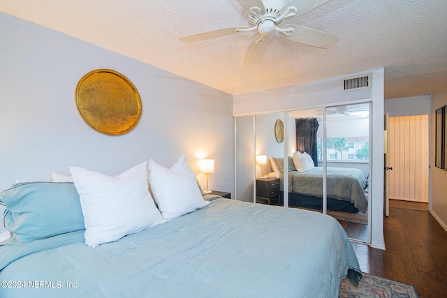 bedroom featuring ceiling fan, a closet, dark wood-type flooring, and a textured ceiling