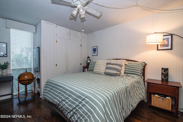 bedroom with dark hardwood / wood-style floors, ceiling fan, and a textured ceiling