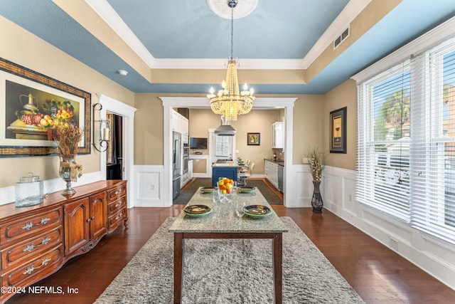 dining area featuring a tray ceiling, ornamental molding, dark wood-type flooring, and an inviting chandelier