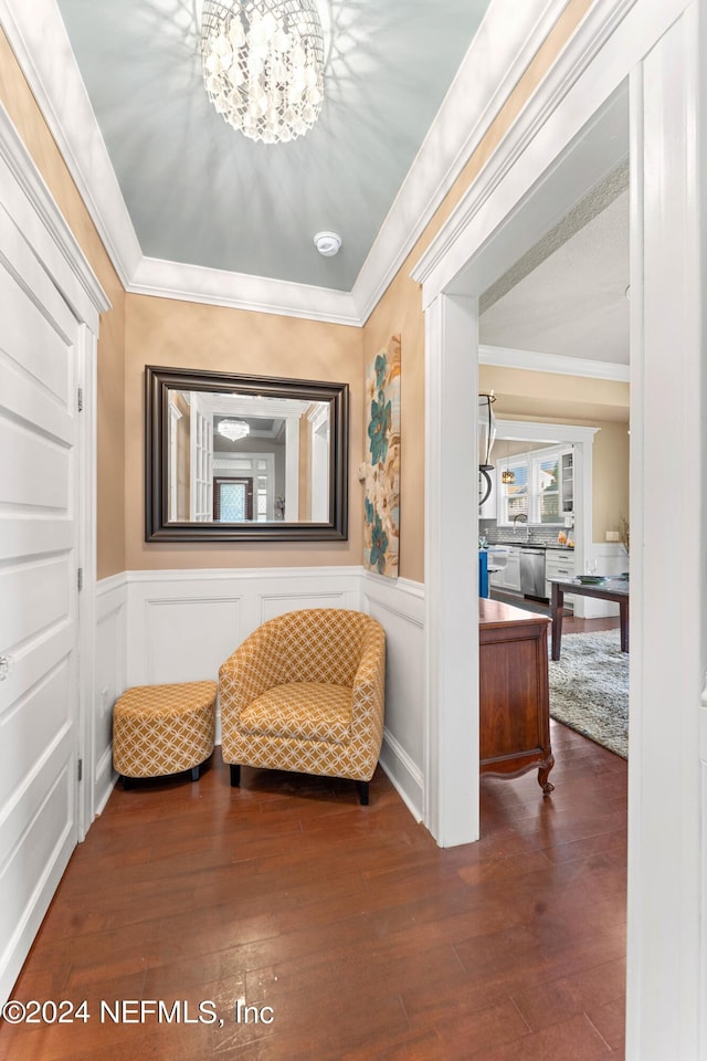 sitting room featuring crown molding, dark hardwood / wood-style floors, and an inviting chandelier