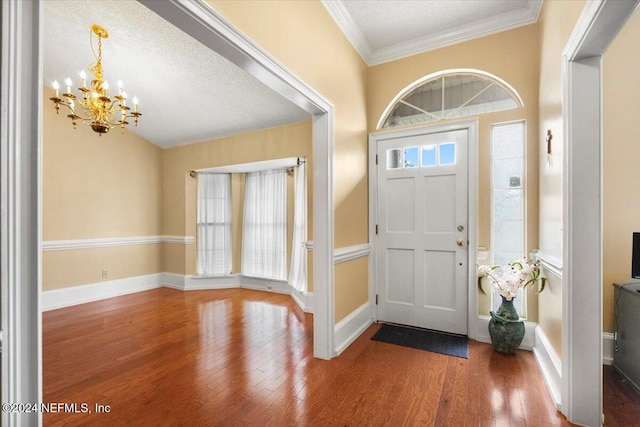 entrance foyer with a chandelier, a textured ceiling, hardwood / wood-style flooring, and ornamental molding