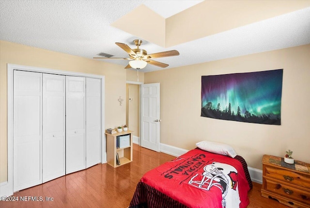 bedroom with ceiling fan, wood-type flooring, a textured ceiling, and a closet